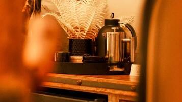 Una encimera de cocina con una cafetera, una planta y un adorno de pared.