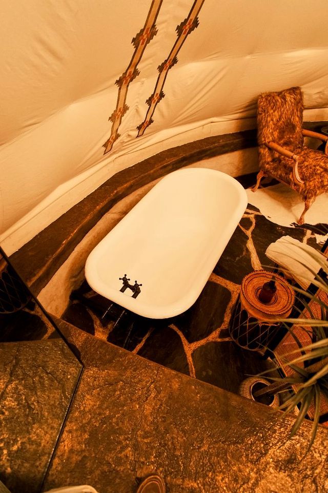 Un baño con una bañera blanca, un perchero para toallas y una cesta de mimbre.