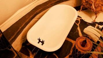 Un baño con una bañera blanca, un perchero para toallas y una cesta de mimbre.