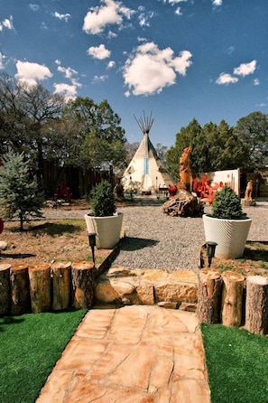 Un tipi tradicional envoltat de plantes en testos i un camí de pedra.