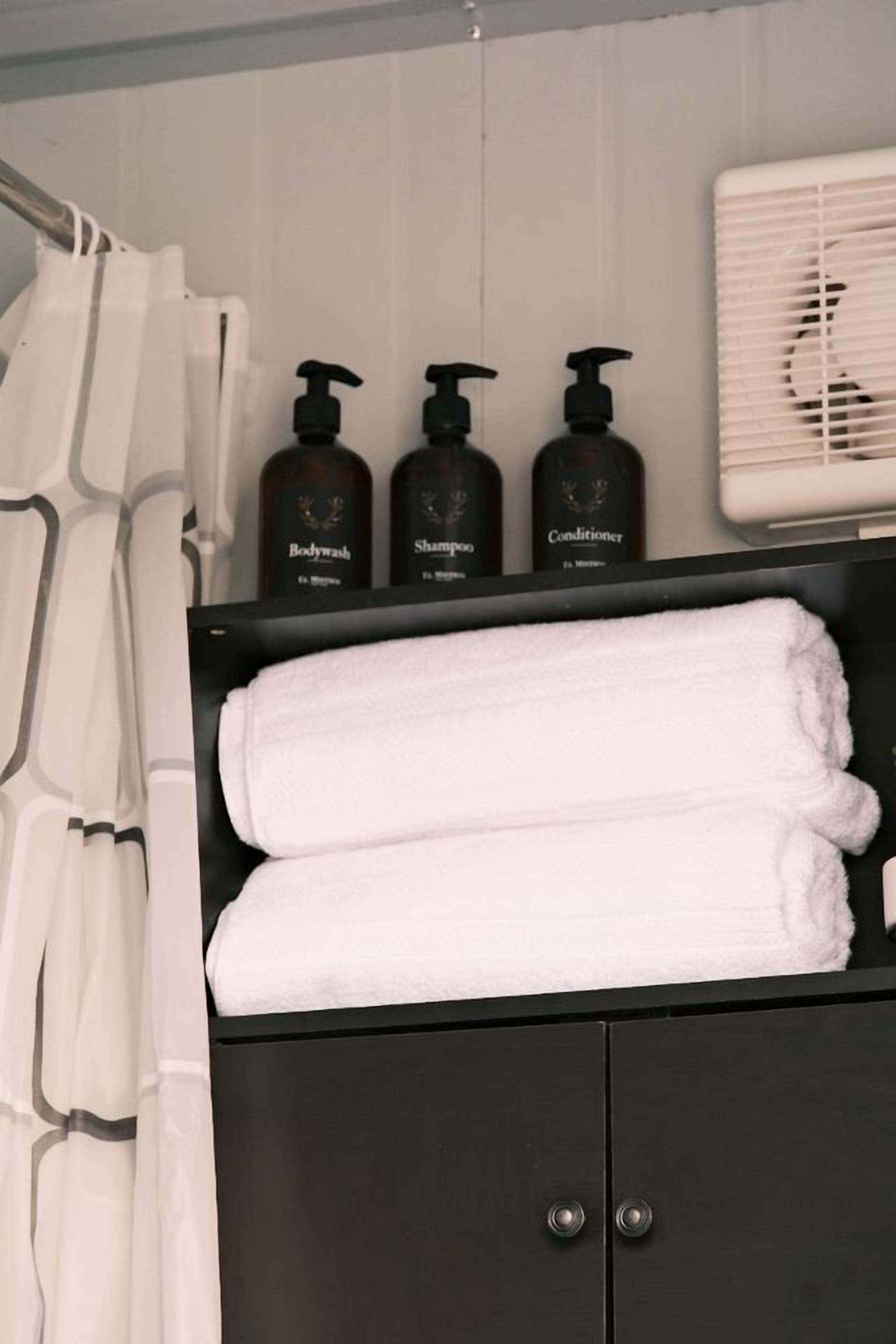 A bathroom with a black cabinet, three bottles of toiletries, and a white towel.