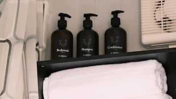 A bathroom with a black cabinet, three bottles of toiletries, and a white towel.
