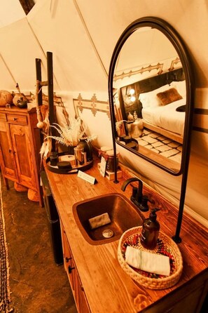 A wooden vanity with a mirror, sink, and a small round tray with a napkin.