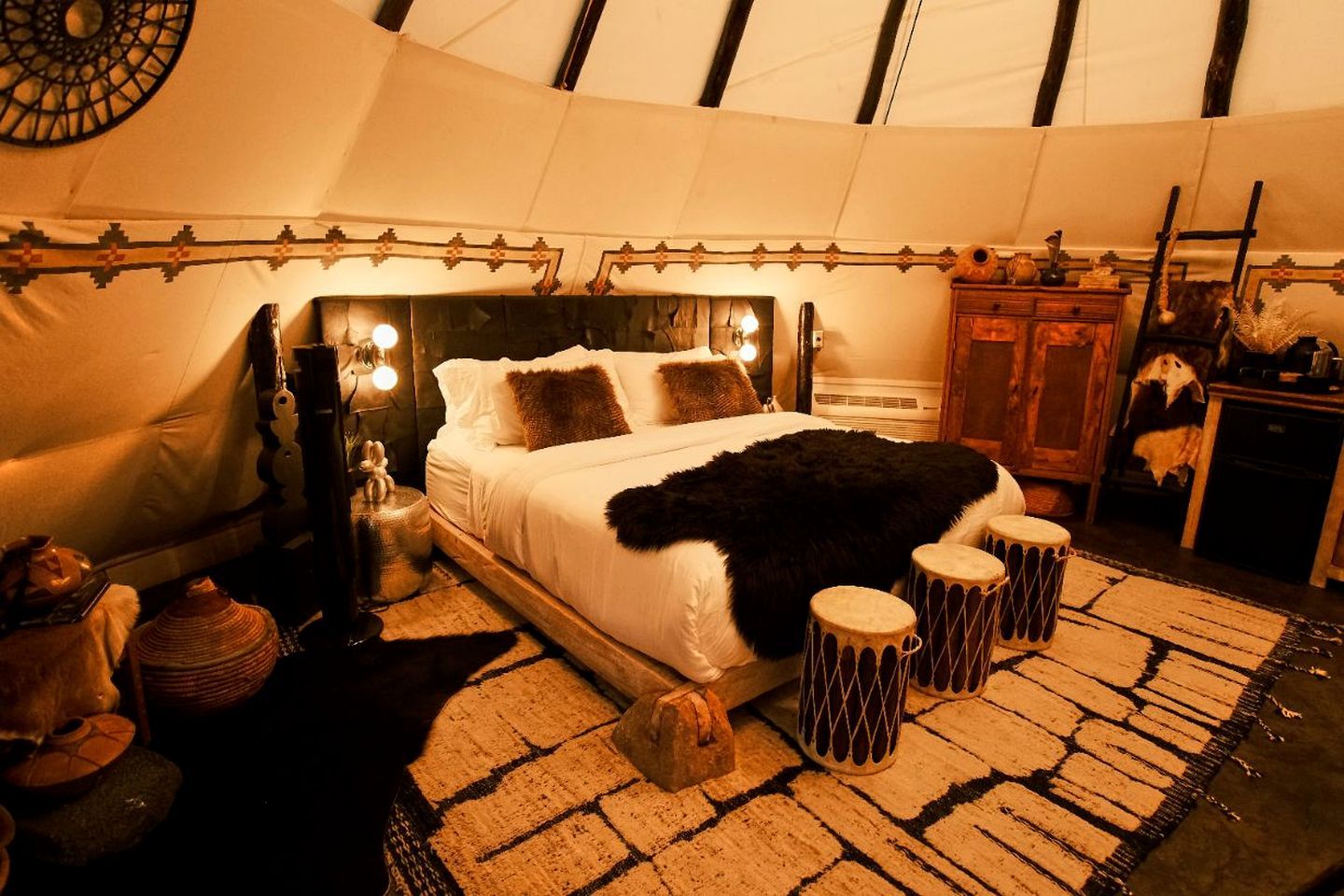 A cozy bedroom with a bed, bedside lamps, a rug, and a wooden cabinet.