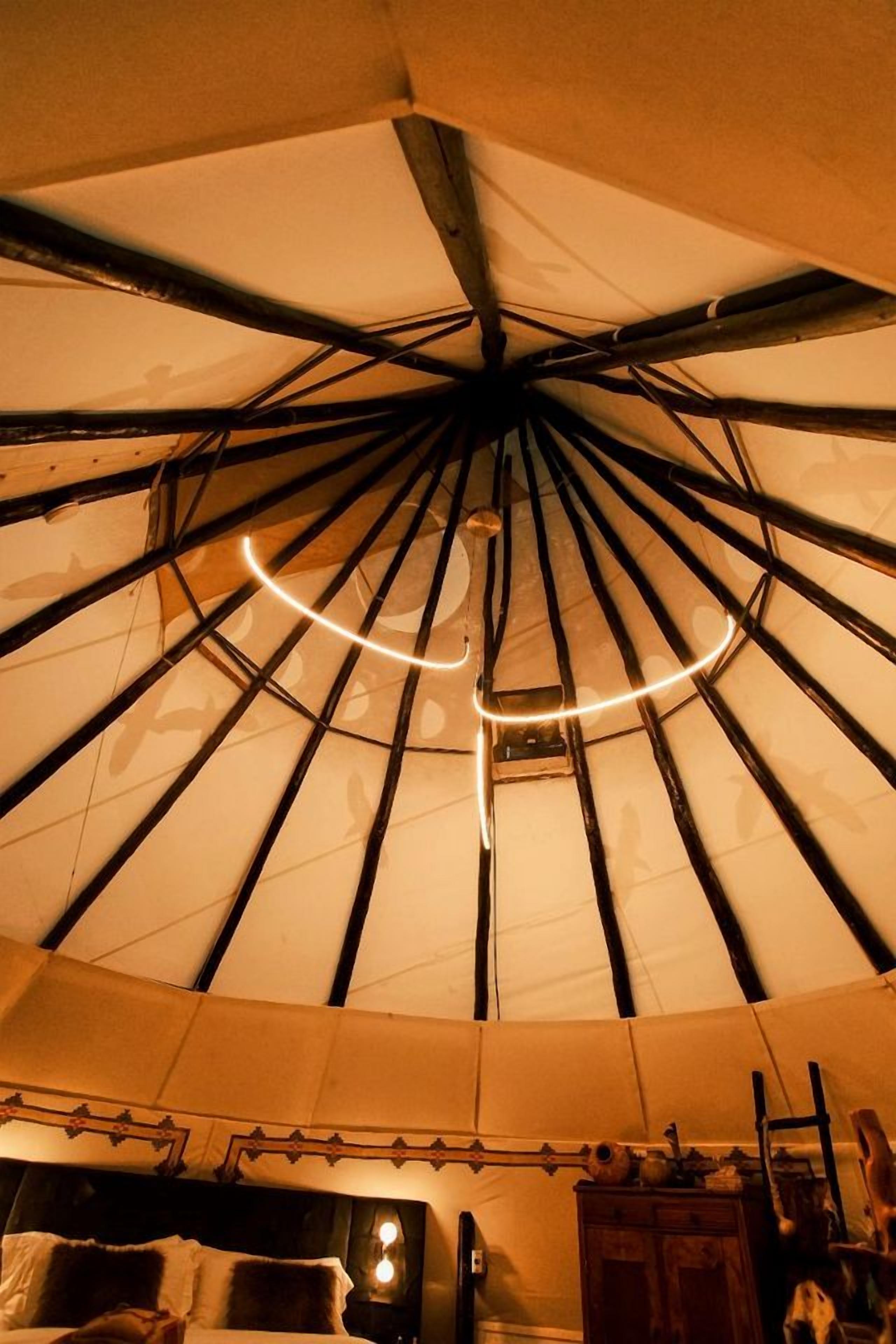 A room with a bed, a wooden cabinet, and a hanging light fixture.