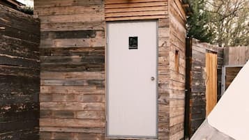 A wooden cabin with a white door, a small porch, and a concrete pathway leading to it.