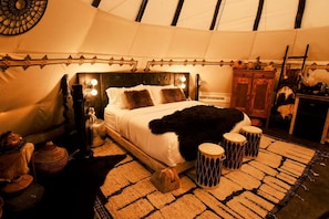 Un dormitorio acogedor con cama, lámparas de noche, una alfombra y un armario de madera.