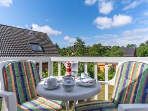 An outdoor seating area with striped chairs and a table set for tea, overlooking a residential area. - Holiday Apartment With 2 Bedrooms (St. Peter-Ording)