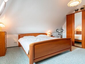 A bedroom with a wooden bed, bedside lamps, a wardrobe, and a mirror. - Holiday Apartment With 2 Bedrooms (St. Peter-Ording)