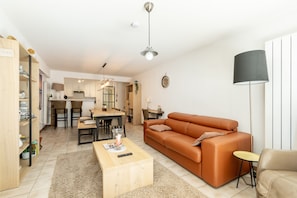 A modern living room with a sofa, coffee table, and a dining area with chairs and a table. - Apartment in Belgium Near the Harbor (Blankenberge)