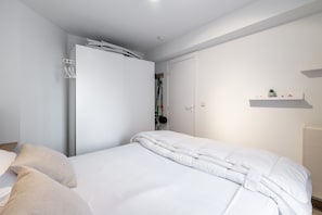 A bedroom with a bed, a wardrobe, and a shelf with a plant. - Apartment in Belgium Near the Harbor (Blankenberge)