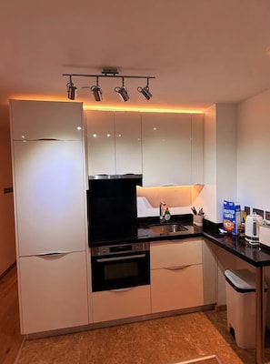 Eine moderne Küche mit weißen Schränken, einer schwarzen Arbeitsplatte und einem eingebauten Backofen.