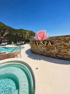 Ein Poolbereich mit einem Schild, auf dem 'SKY SPA' steht, und einer großen, pinkfarbenen Lotusblumen-Dekoration.