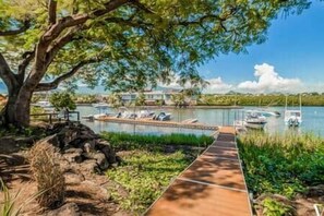 A wooden dock leading to a calm lake with boats, surrounded by greenery and a large tree. - Luxury Penthouse with Private Pool (Grande Riviere Noire)
