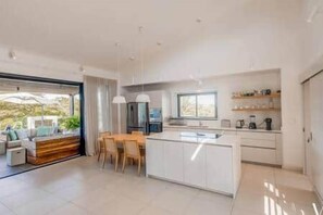 A modern kitchen with a central island, dining area with chairs, and a large window providing natural light. - Luxury Penthouse with Private Pool (Grande Riviere Noire)