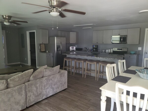 A modern kitchen with a central island, bar stools, and a dining table with chairs.