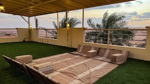 Un espacio de estar al aire libre techado con vista a la playa y palmeras.