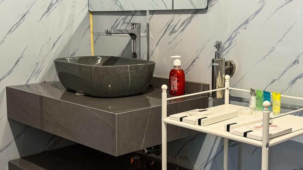 A modern bathroom with a large vessel sink, a mirror, and a white vanity with a soap dispenser.