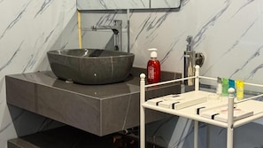 Ein modernes Badezimmer mit einem großzügigen Aufsatzwaschbecken, einem Spiegel und einer weißen Waschtischkommode mit Seifenspender.
