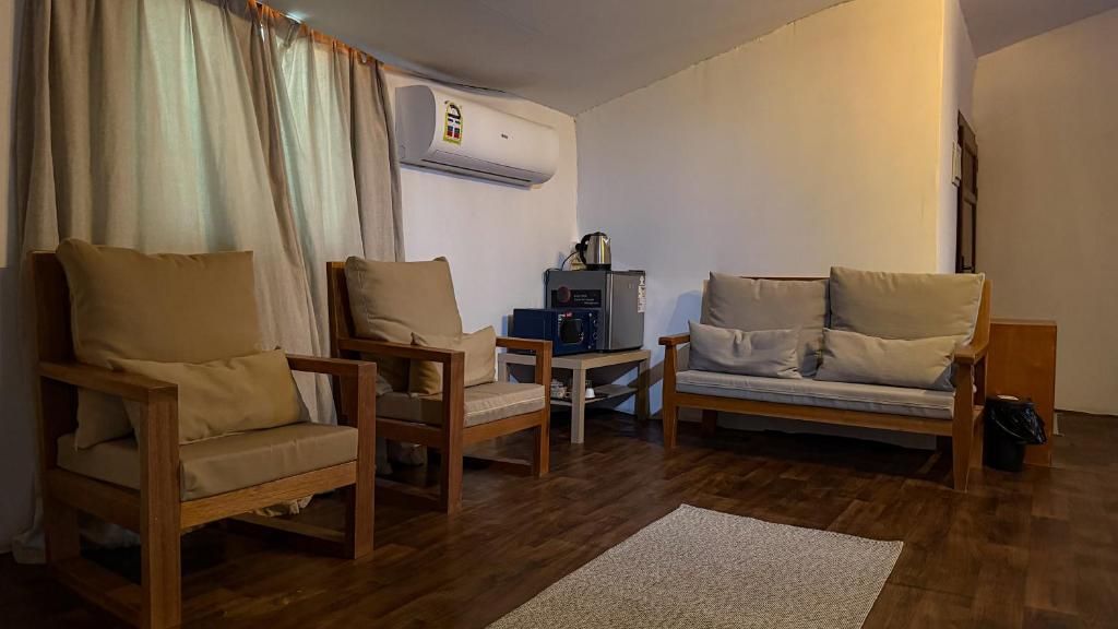 Una sala de estar con sofá, dos sillones, una mesa de centro y un equipo de aire acondicionado.