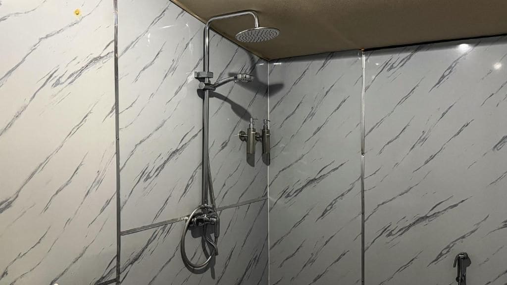 Une douche équipée d’un pommeau de douche à main et d’un robinet fixé au mur.