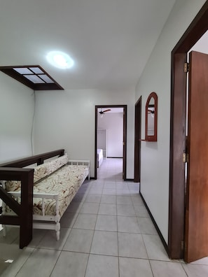 A hallway with a bed, a ceiling fan, and a door leading to another room.
