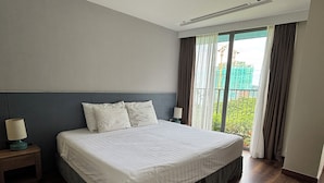 Een hotelkamer met een groot bed, een nachtkastje, een lamp en uitzicht op een bouwplaats.