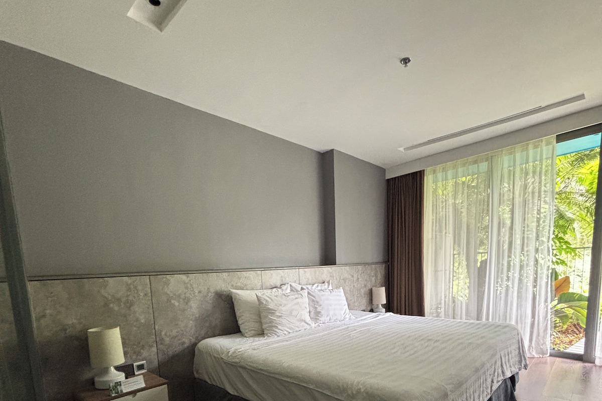 A modern bedroom with a large bed, a nightstand, and a window with curtains.