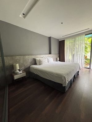 A modern bedroom with a large bed, a nightstand, and a window with curtains. - Blue Sea & Sand Cat Ba Resort (Cat Ba Island)