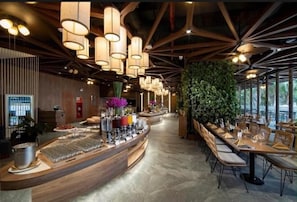 A restaurant interior with a long counter, hanging pendant lights, and a green wall. - Blue Sea & Sand Cat Ba Resort (Cat Ba Island)