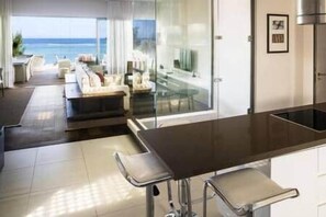 Eine moderne Küche mit dunkler Arbeitsplatte, einer Bar mit Hockern und Blick auf den Ozean.