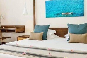 Ein Hotelzimmer mit Bett, Kissen, Schreibtisch und einem Bild eines Bootes an der Wand.