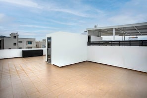 A rooftop terrace with a flat roof, a door, and a wall with a black railing. - Stylish Central Three Bed Duplex with Private Pool (Flic en Flac)