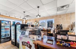 A fast-food restaurant interior with a counter, refrigerated beverage display, and a menu board. - Tidewater 1605- Sunset Dreams (Panama City Beach)