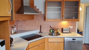 Una cocina con armarios de madera, un lavamanos de acero inoxidable, un tostador y un lavavajillas.