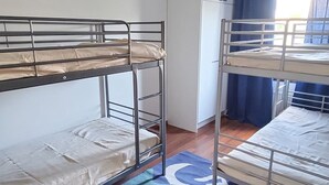 Un dormitorio con literas, una ventana con cortinas y una puerta.