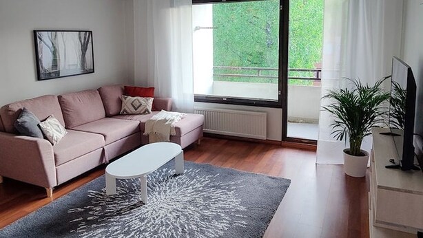 Una sala de estar moderna con un sofá, una mesa de centro, una planta en maceta y un televisor.