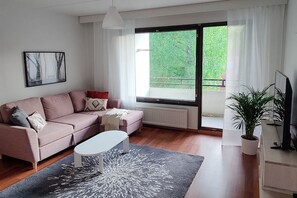 A modern living room with a sofa, a coffee table, a potted plant, and a television.