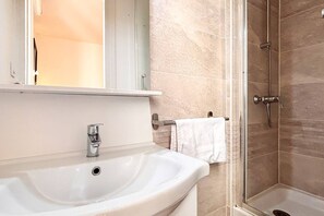 Une salle de bain équipée d’un lavabo, d’un miroir, d’un porte-serviettes et d’une douche.