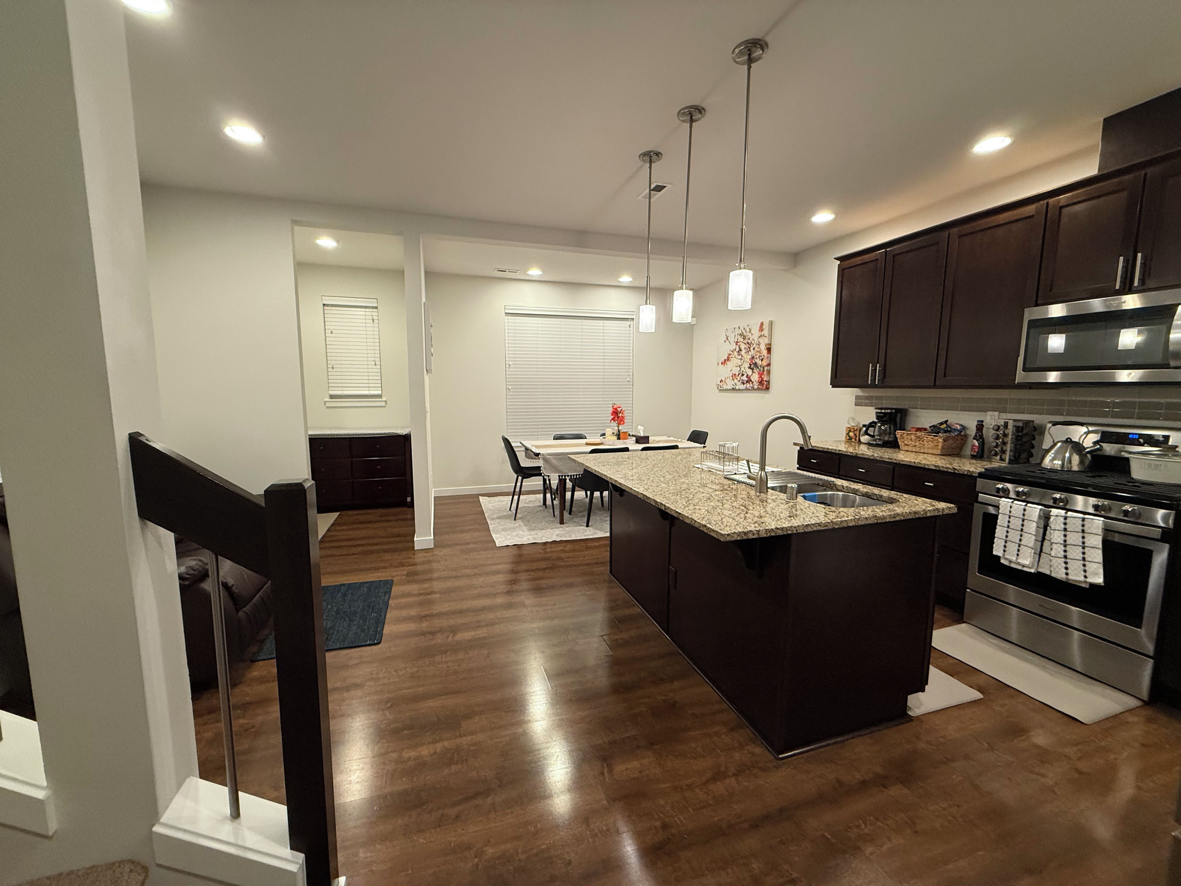 A modern kitchen with granite countertops, stainless steel appliances, and pendant lighting.