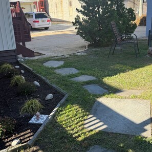 A garden with stepping stones, a bench, and a car parked on the street. - THE ARTFUL TIDE - Unit B/Beautiful 2 BR/1BA Mansion Suite (Atlantic City)