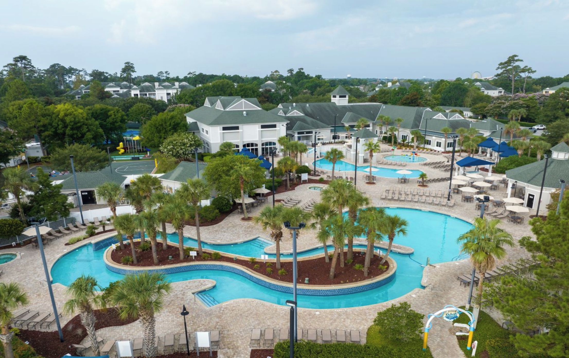 A resort with multiple swimming pools, palm trees, and lounge areas.