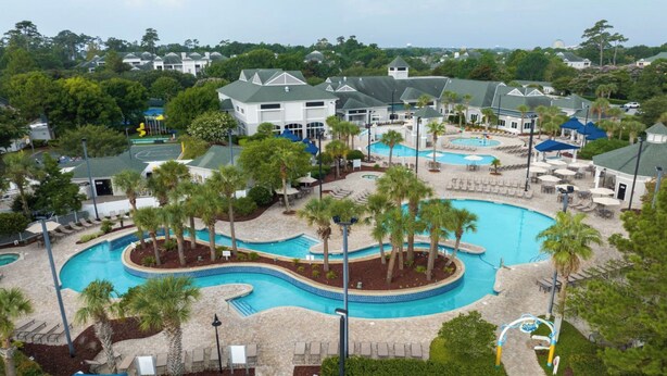Een resort met diverse zwembaden, palmbomen en terrasjes.