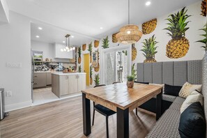 A modern kitchen with a dining area, featuring a wooden table and a patterned sofa. - Downtown West Palm Beach Posh Pinneapple (West Palm Beach)