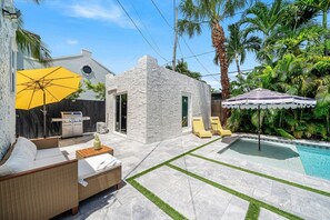 Un jardin avec une piscine, du mobilier d’extérieur et un espace barbecue.