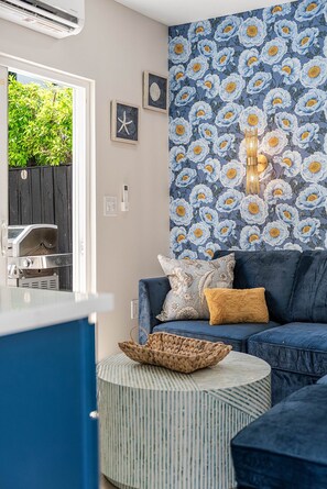 Un salon avec un canapé bleu, une table basse ronde et un papier peint à motifs.