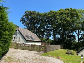 A single-story building with a sloped roof, a wooden fence, and a gravel driveway. - Cottage Sleeps 4 Indoor Pool, Fishing Lake, Pets (Beaworthy)