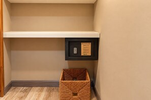 A hallway with a wooden floor, a white shelf, and a black storage unit with a lock and a notice. - Central Sosua 1BR , Balcony , Hard Rock Perks (San Felipe de Puerto Plta)