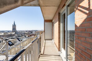 Ein Balkon mit Blick auf eine Stadtlandschaft und einen Kirchturm.
