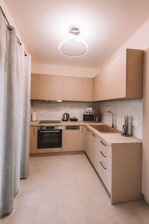 A compact kitchen with a modern design, featuring a built-in oven, microwave, and a sink with a faucet.